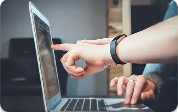 A person pointing at a laptop screen during a video call.